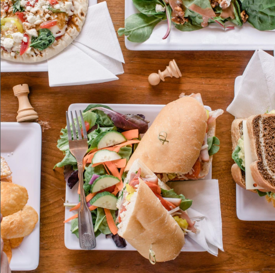 Sandwich and a salad on a plate on a wooden table.