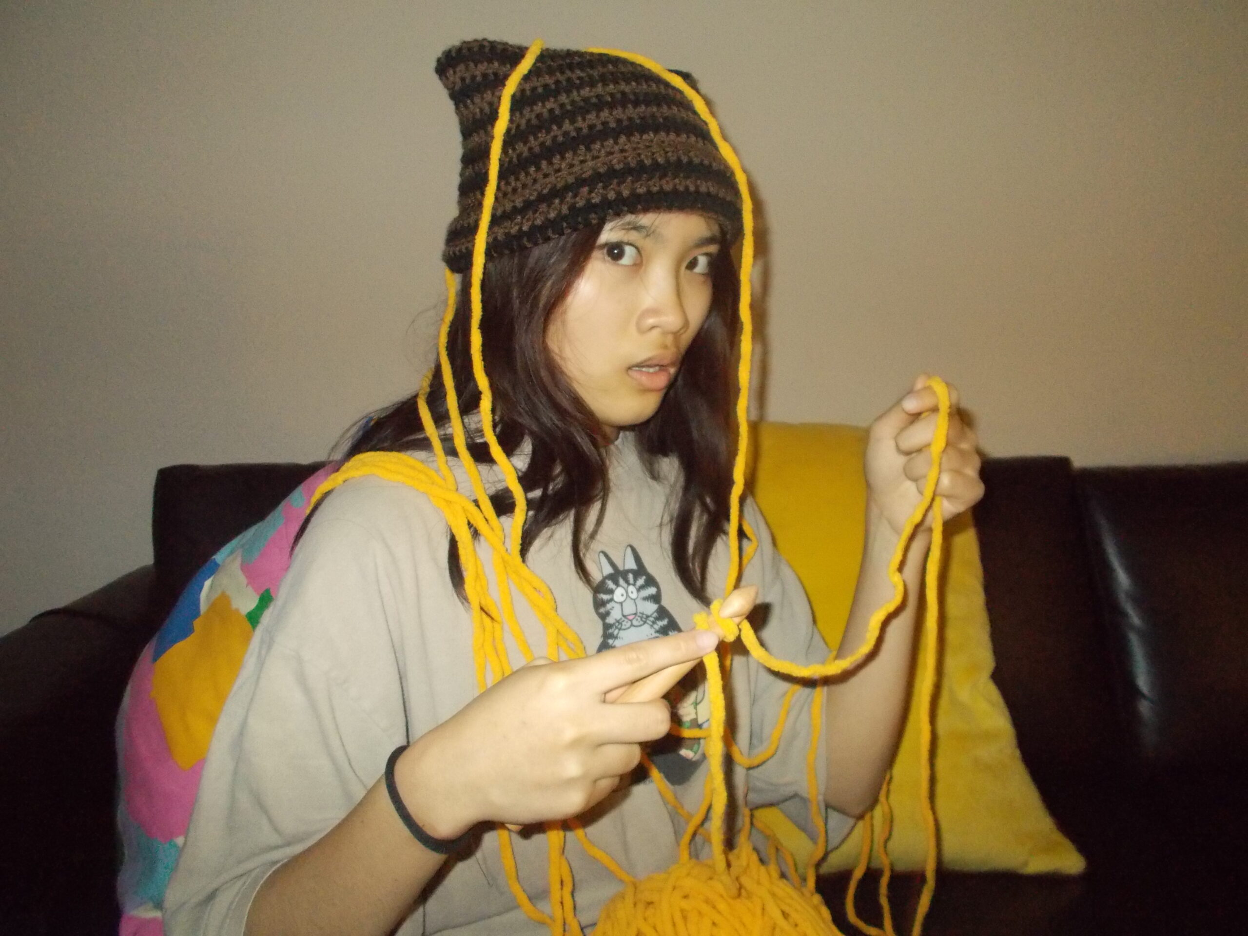Amanda wearing a cat beanie tangled in yarn.