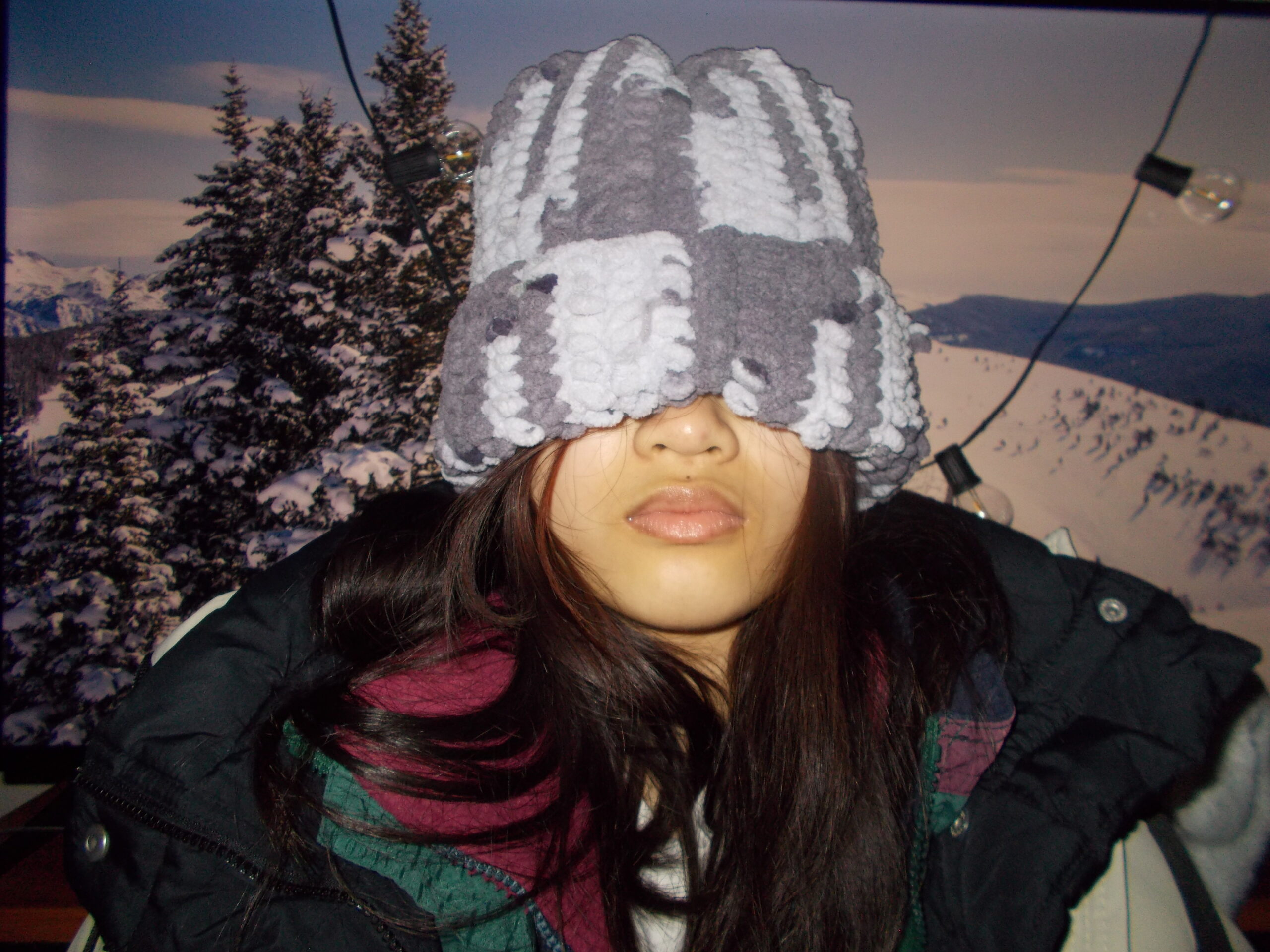 Amanda wearing three puffy jackets and a chunky beanie in the snowy mountains.