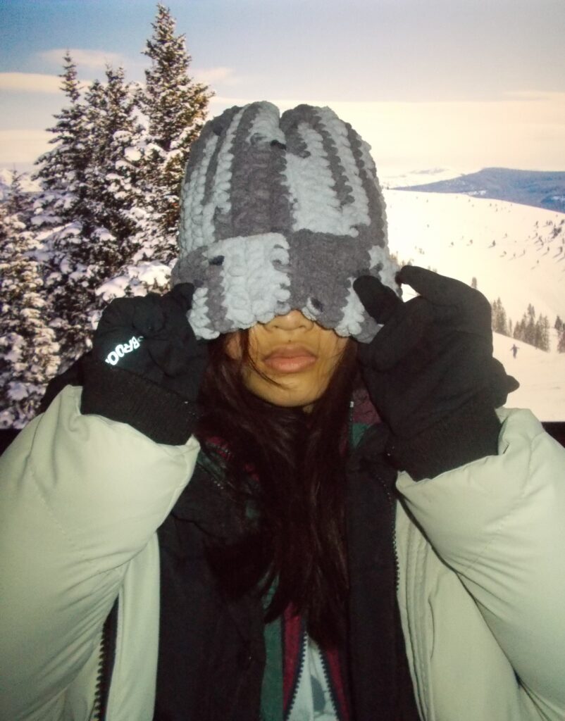 Amanda wearing the chunky beanie and three puffer jackets in the snowy mountains.