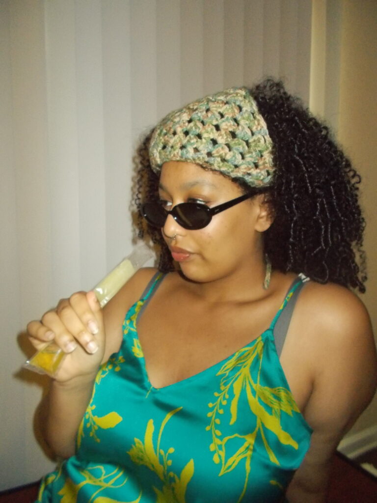 Hannah wearing the bandana and sunglasses eating a popsicle.