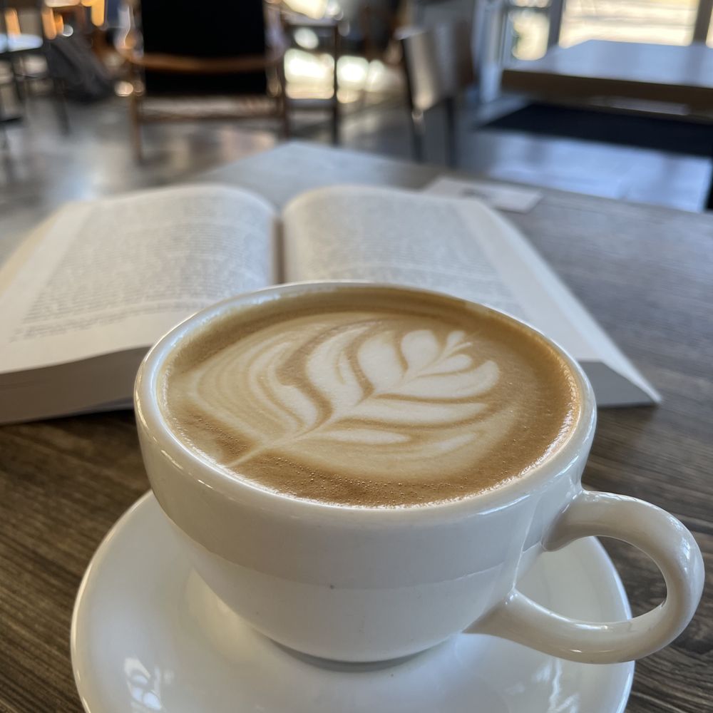 Coffee with foam design next to an open book.