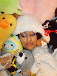 Hannah wearing the fluffy beanie surrounded by stuffed animals