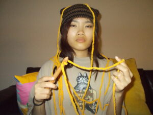 Amanda wearing the cat beanie and tangled in yarn.
